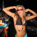 Beautiful girl in a bikini bartending wearing glasses.